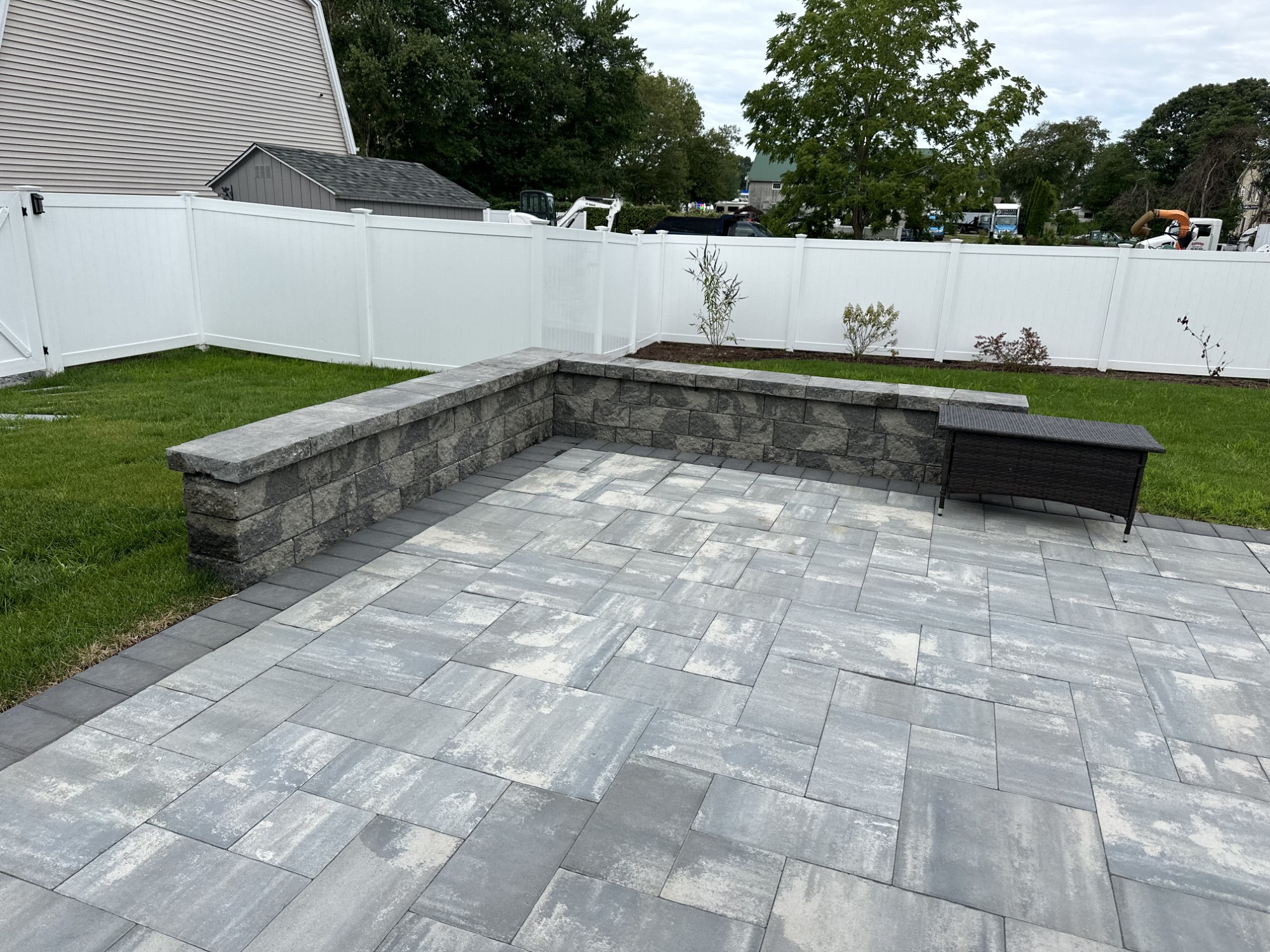 Completed paver patio and stone sitting wall in a landscaped backyard